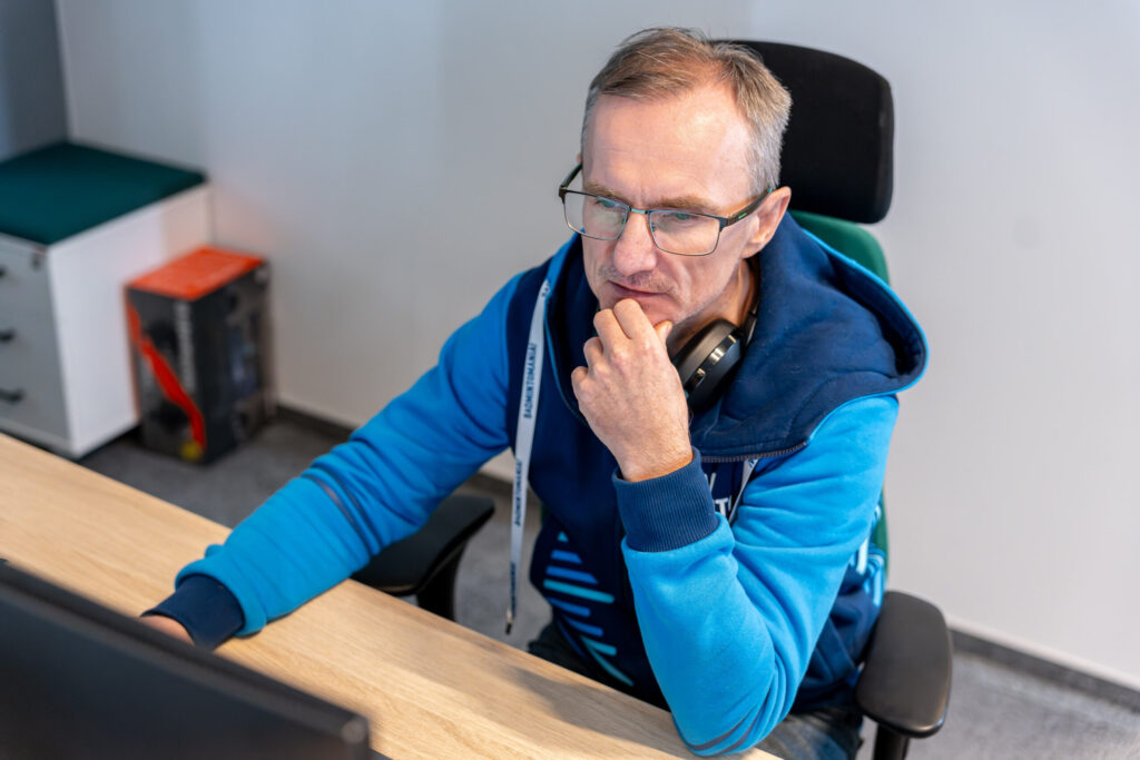 A man in a blue sweatshirt works in front of a computer