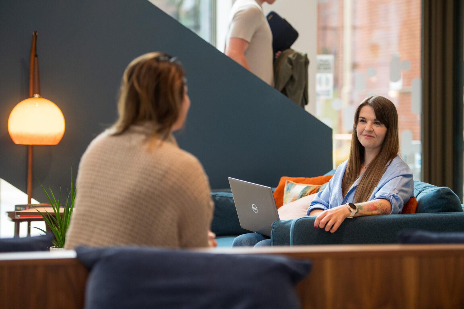 Two female employees of Spyrosoft in Manchester talk to each other in the common area of ​​the building