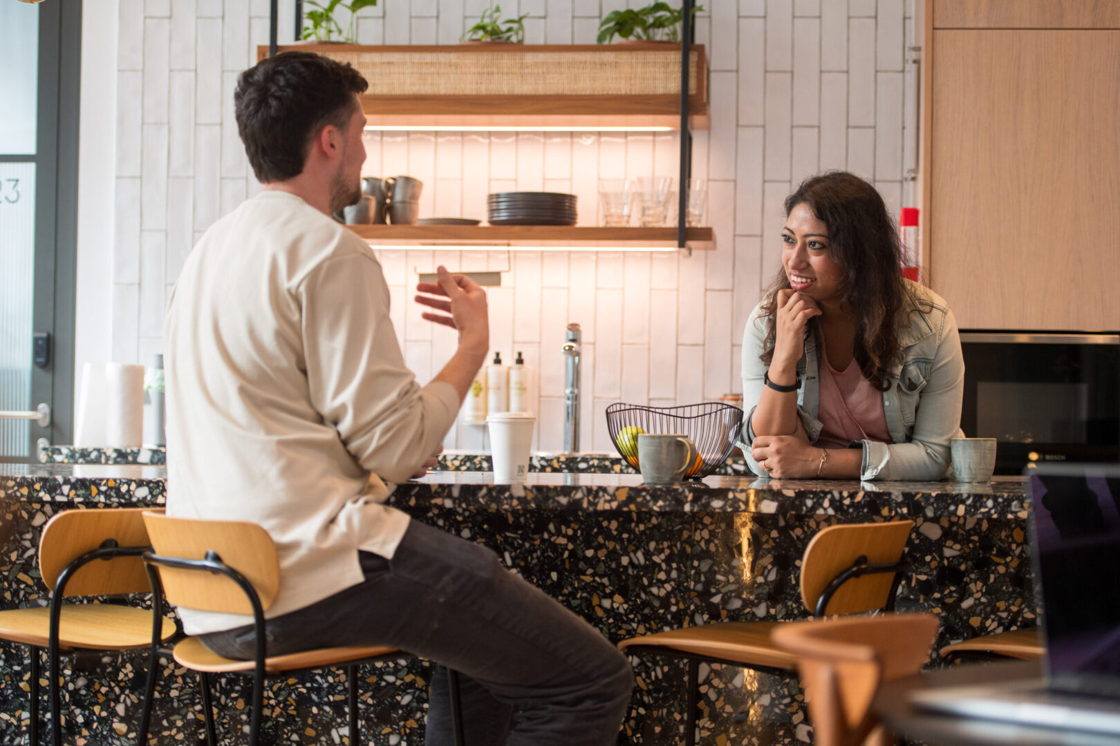 A woman and a man, employees of the Spyrosoft site in Manchester, talk to each other in the staff kitchen.