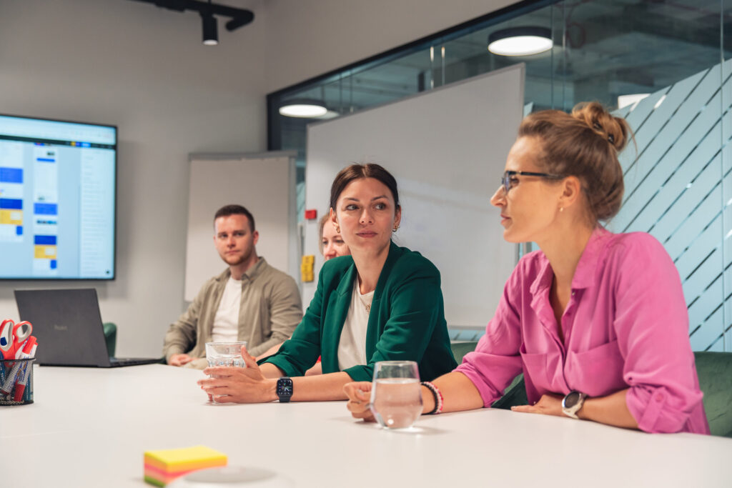 Spyrosoft employees participate in a meeting together, two women are in the foreground of the photo