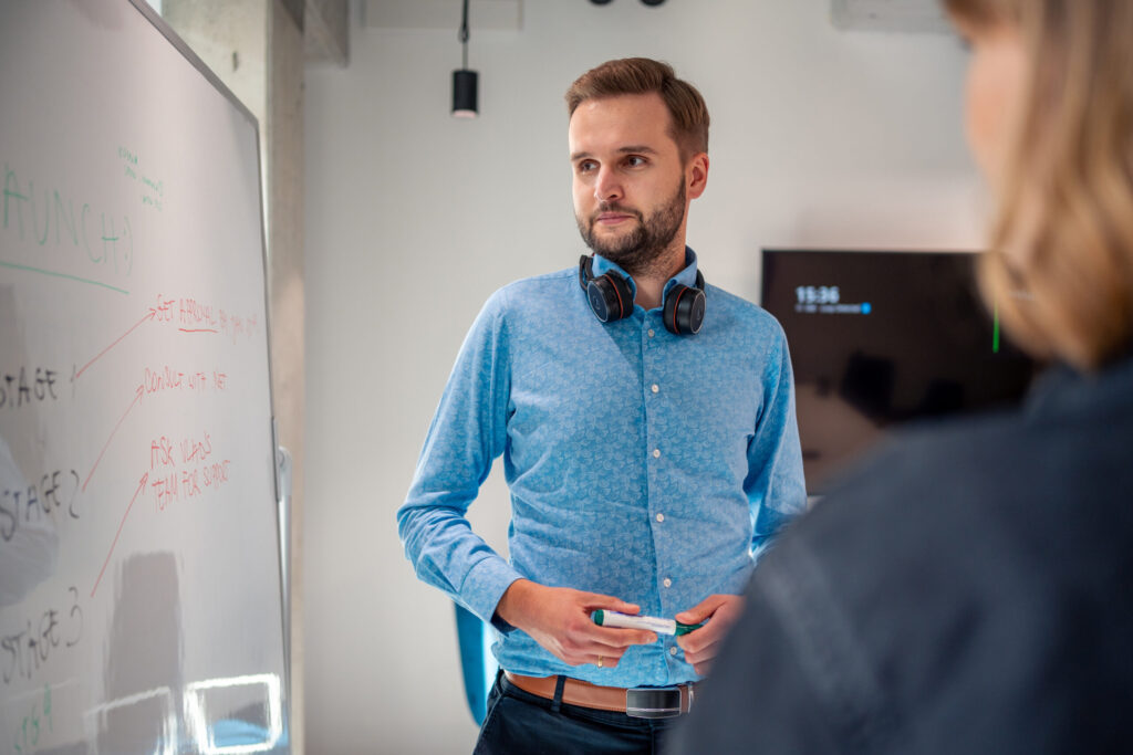 A woman and a man, employees of Spyrosoft in Wroclaw, are writing out the project stages on a whiteboard.