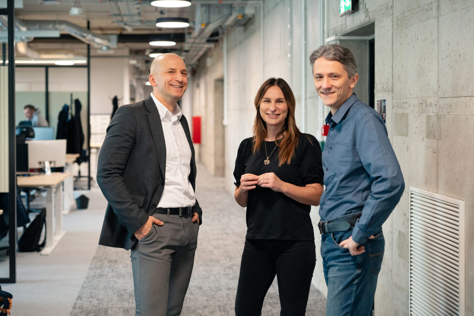 Two men and a woman are talking in the hallway of the Spyrosoft Synergy office space in Szczecin.