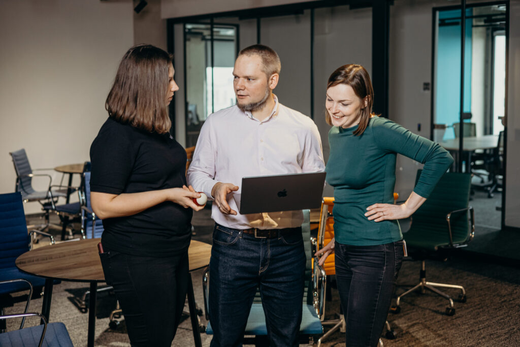 Three people, two women and a man, discuss tasks in the Spyrosoft office in Lodz.
