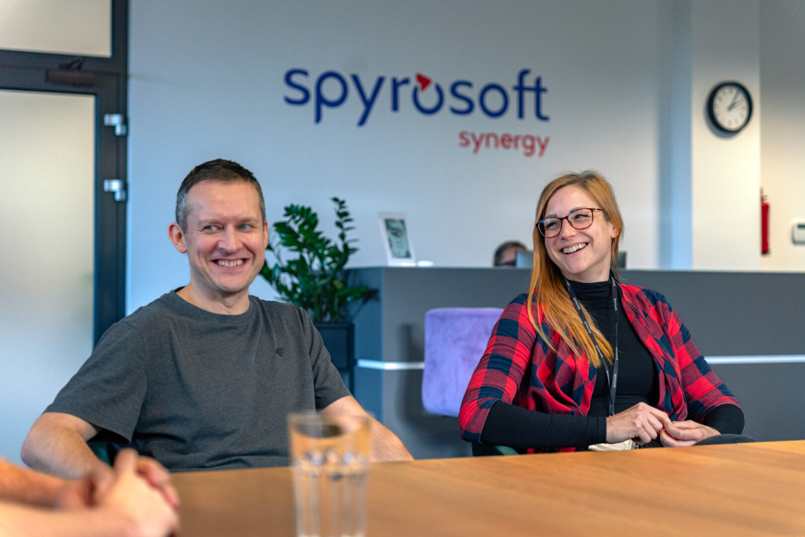 A woman and a man sit at a conference table in the Spyrosoft office in Szczecin. Smiles can be seen on their faces.