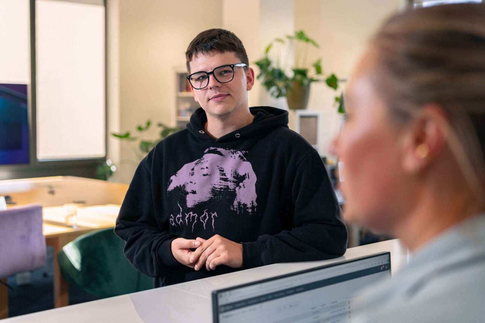 A woman and a man are talking to each other at the reception desk of Spyrosoft Synergy in Szczecin.