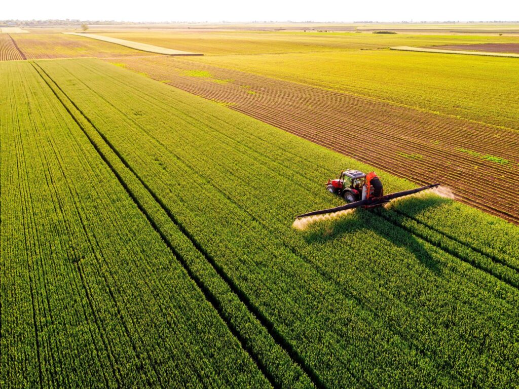 Aerial view of a farmer driving a tractor on a green field of a innovative agricultural business